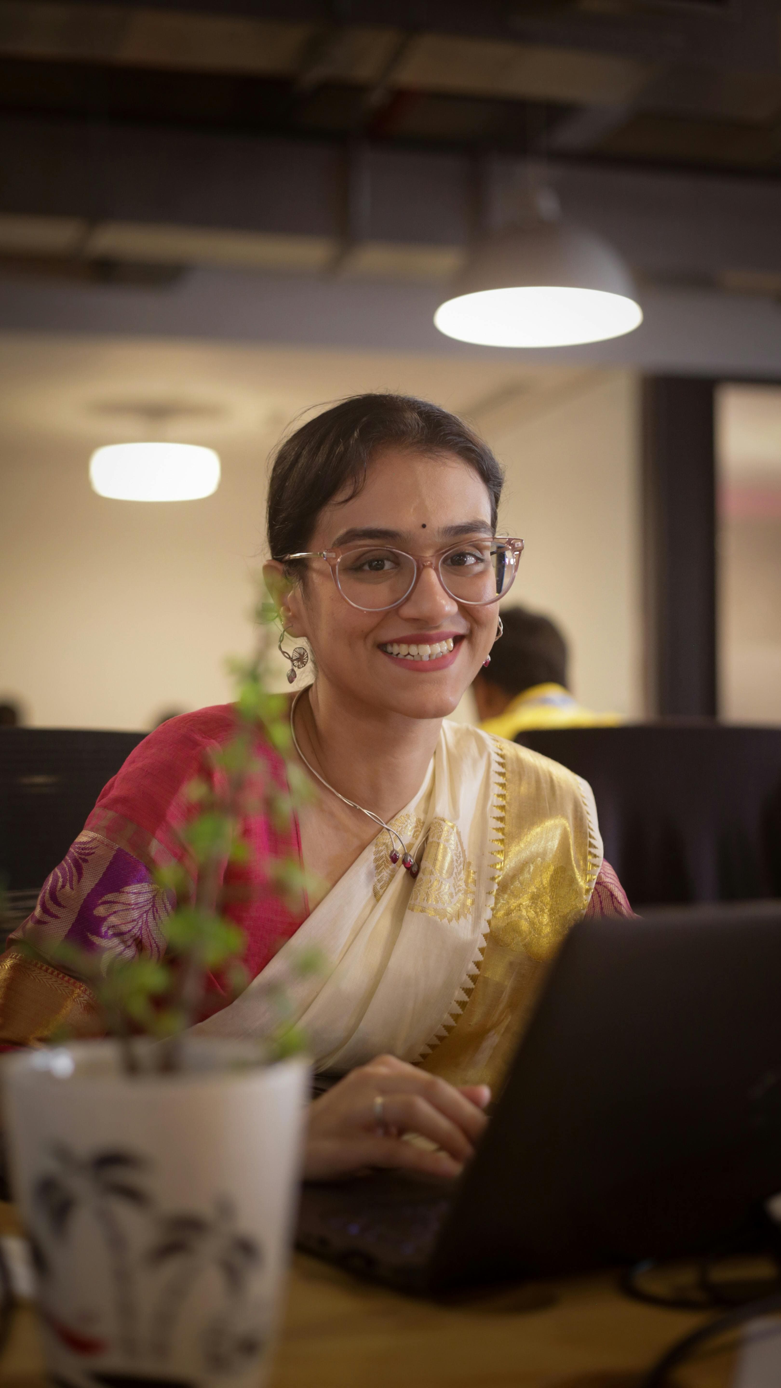Support staff using a laptop to track application progress in an Indian office